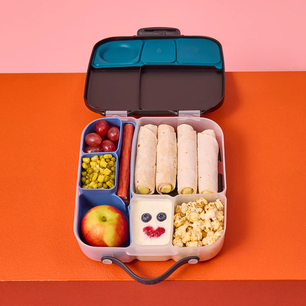 Bento box lunchbox with silicone lunchbox divider food tray and various food items including wraps, fruits, and popcorn on a colorful background