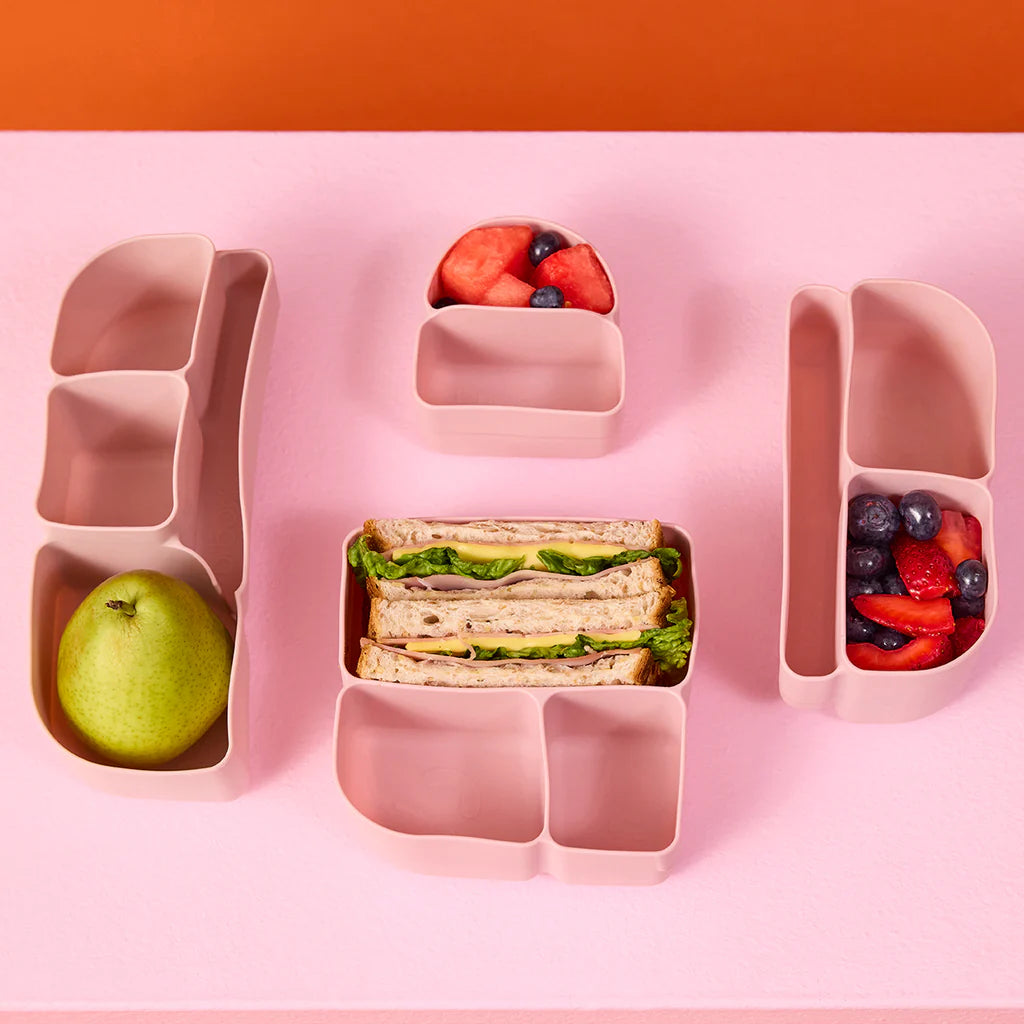 b.box lunchbox with b.box berry lunchbox divider container with sandwich, apple, and fruit on a pink background