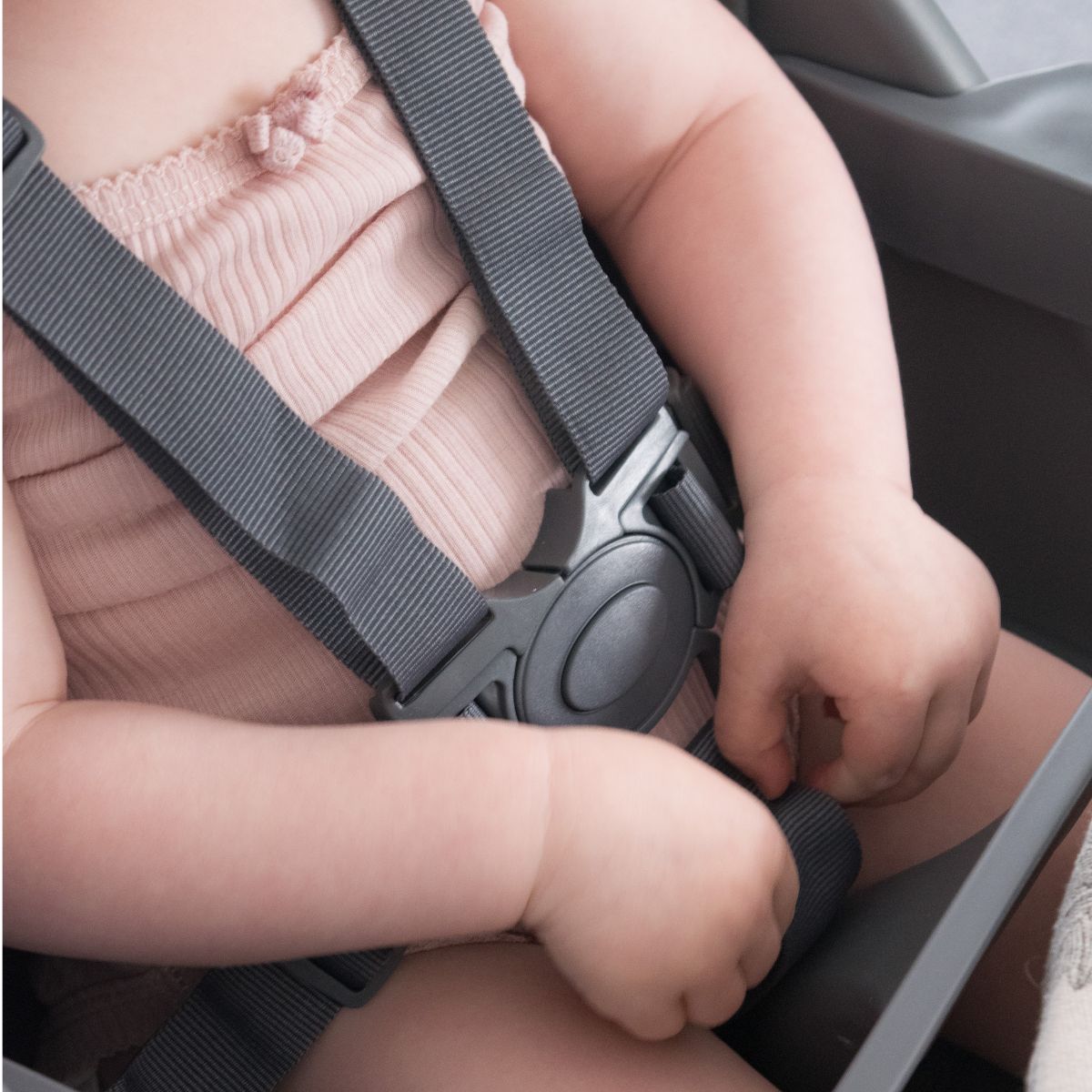 Close-up of the five-point harness buckle fastened around a toddler in the Moose Harper highchair