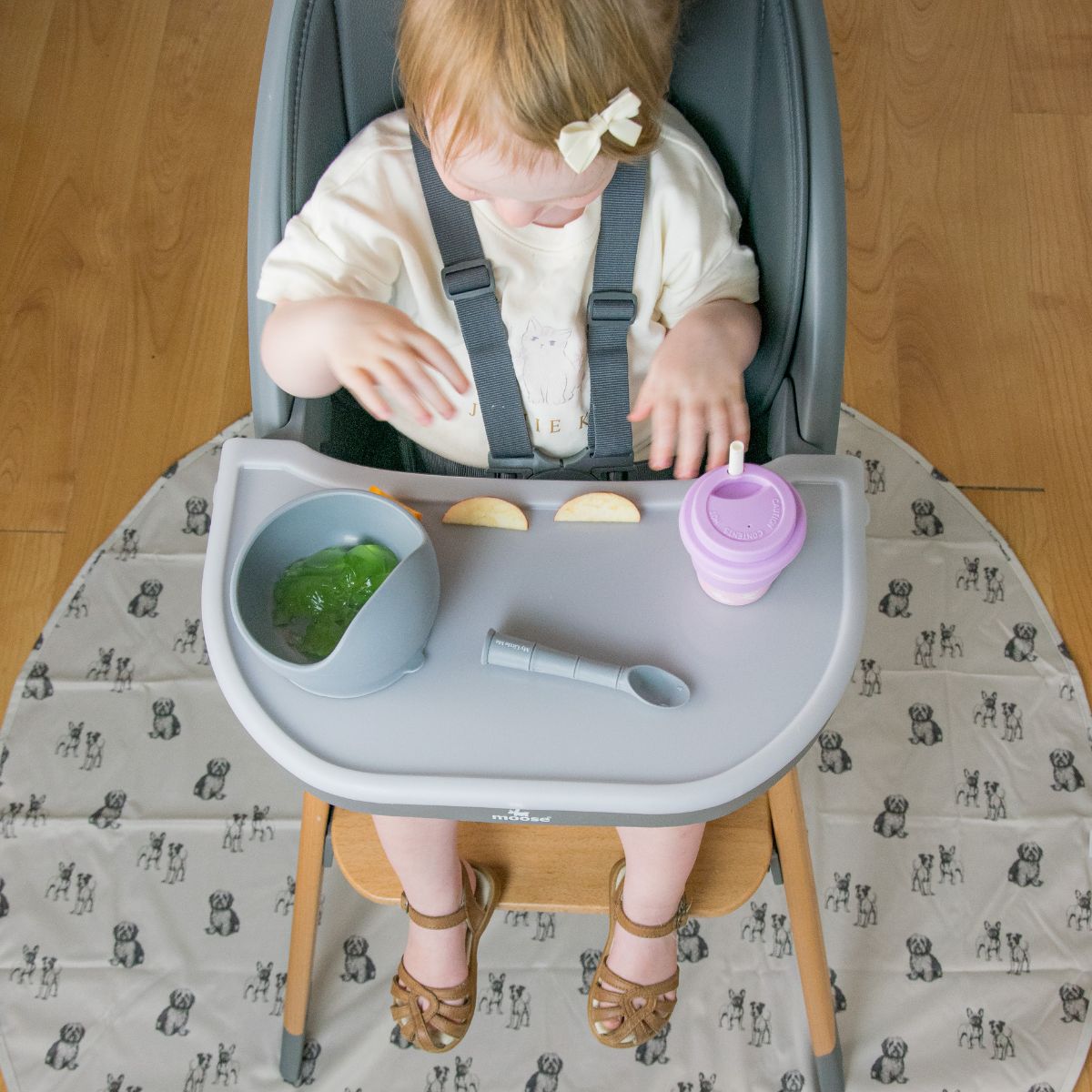 Overhead view of a toddler eating in the Moose Harper highchair above an animal print floor mat